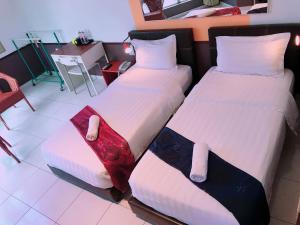 a hotel room with two beds and a chair at Langit Langi Hotel @ KLIA/KLIA2 in Kampung Dengkil