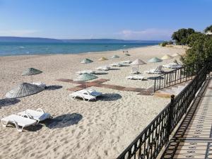 恰納卡萊的住宿－艾瑞斯酒店，海滩上设有遮阳伞和椅子,还有大海