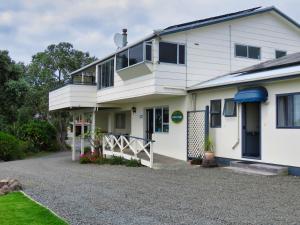 a white house with a porch and a driveway at Pukenui Lodge Motel in Pukenui
