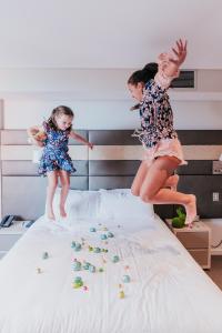 
a girl and a boy are playing on a bed at Novotel Newcastle Beach in Newcastle
