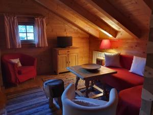 salon z czerwoną kanapą i stołem w obiekcie Appartement Pension Bäckenhäusl FERIENWOHNUNGEN Chalets Hütten Komfortzimmer w mieście Uttendorf