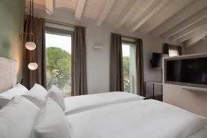 Schlafzimmer mit einem weißen Bett und einem TV in der Unterkunft HT Hotel Trieste in Gradisca dʼIsonzo