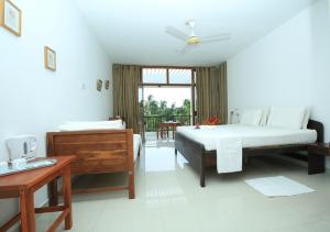 a bedroom with two beds and a table and a window at High Park Hotel in Nilaveli