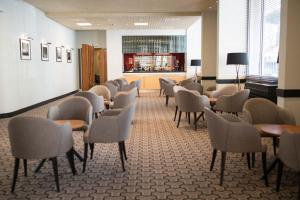 a waiting room with chairs and tables and a bar at Lancaster Hall Hotel in London