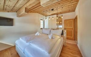 a large white bed in a room with wooden ceilings at Apartment Panorama in Saalbach Hinterglemm