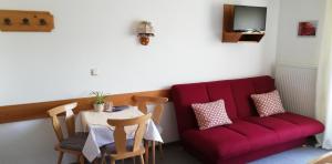 een woonkamer met een rode bank en een tafel bij Sonneck Pension in Pfarrwerfen