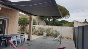 a patio with a table and chairs and a blue umbrella at Mes maisons à la Pinède in Sainte-Maxime