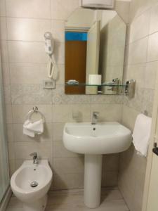 uma casa de banho com um lavatório, um espelho e um WC. em Hotel Centrale Europa em Catânia