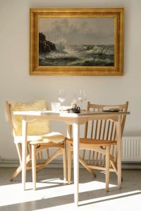 a white dining room table with two chairs and a painting at Grønbechs Hotel in Allinge