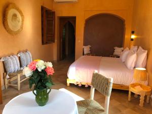 - une chambre avec un lit et un vase de fleurs sur une table dans l'établissement Domaine Casa Cecilia, à Marrakech