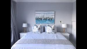 a bedroom with a white bed with a painting on the wall at Sorgente 304 with Inverter in Umdloti