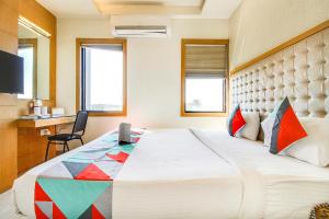 a bedroom with a large bed and a desk at FabHotel Naman Palace in Bhopal