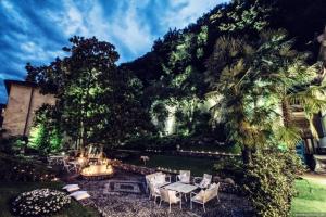 un giardino con tavolo, sedie e montagna di Boutique Hotel Villa Giulia a Valmadrera