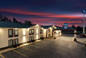 a hotel with a parking lot at dusk at Baymont by Wyndham Caddo Valley/Arkadelphia in Arkadelphia