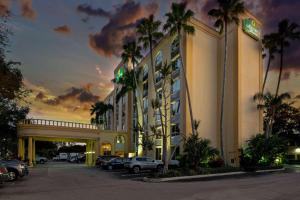 a hotel with cars parked in a parking lot at La Quinta by Wyndham West Palm Beach Airport in West Palm Beach