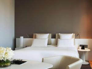
a white bed with white pillows and pillows at Pullman Brussels Centre Midi in Brussels
