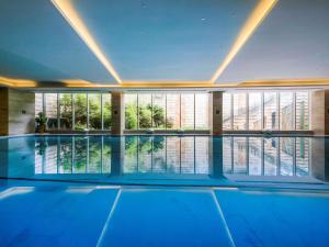 a large swimming pool in a building with a large window at Pullman Linyi Lushang in Linyi