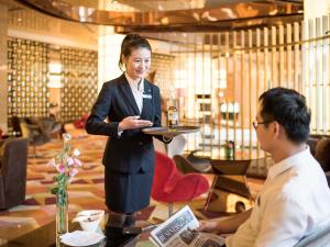 a woman standing in a lobby with a table with a man at Pullman Linyi Lushang in Linyi