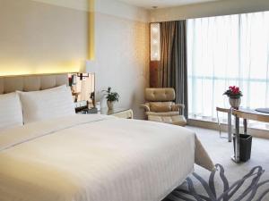 a hotel room with a large bed and a chair at Pullman Linyi Lushang in Linyi