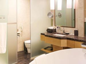 a bathroom with a sink and a toilet and a mirror at Pullman Linyi Lushang in Linyi
