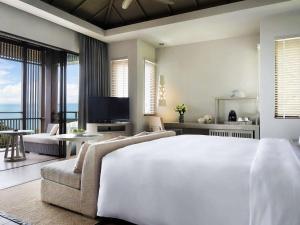 a bedroom with a large white bed and a couch at Pullman Phuket Arcadia Naithon Beach in Nai Thon Beach