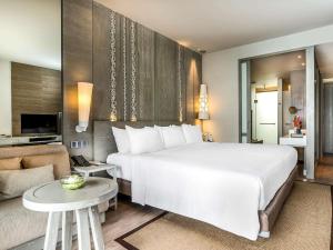 um quarto com uma grande cama branca e uma sala de estar em Pullman Phuket Arcadia Naithon Beach em Praia de Nai Thon