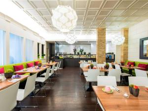 a restaurant with wooden tables and white chairs at Ibis Styles Frankfurt City in Frankfurt
