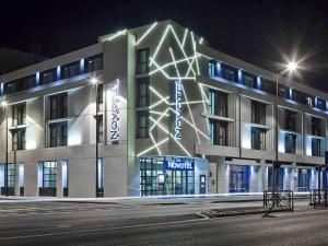 un bâtiment avec une façade éclairée la nuit dans l'établissement Novotel Avignon Centre, à Avignon