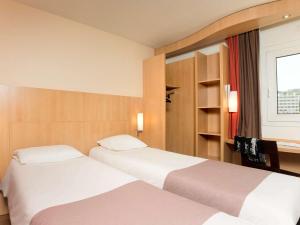 イシー・レ・ムリノーにあるアイビス イッシー レ ムリノ ヴァル ド セーヌのベッド2台と窓が備わるホテルルームです。