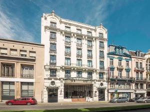 ein großes weißes Gebäude mit davor geparkt in der Unterkunft Mercure Lille Roubaix Grand Hôtel in Roubaix