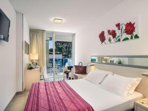 a bedroom with a bed with a pink blanket on it at Mercure Hotel Rimini Artis in Rimini