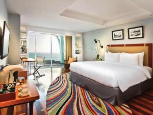a hotel room with a large bed and a living room at The Kuta Beach Heritage Hotel - Managed by Accor in Kuta