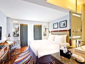 una camera d'albergo con un grande letto e una scrivania di The Kuta Beach Heritage Hotel - Managed by Accor a Kuta