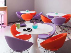 um grupo de mesas e cadeiras numa sala em ibis Styles Montbéliard em Montbéliard