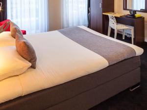 Bett in einem Hotelzimmer mit einem Tisch und einem Schreibtisch in der Unterkunft ibis Styles Amsterdam City in Amsterdam