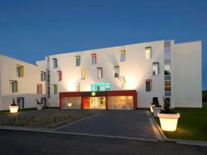 - un grand bâtiment blanc avec des fenêtres colorées dans l'établissement ibis Styles Nivelles, à Nivelles