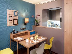 a dining room with a table and yellow chairs at Aparthotel Adagio Köln City in Cologne