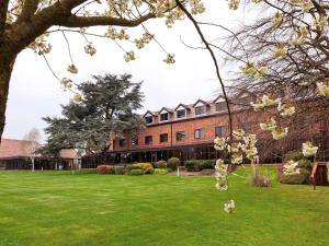 um grande edifício de tijolos com um pátio verde em Mercure Hull Grange Park Hotel em Hull