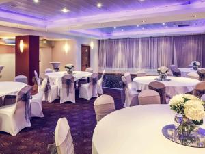 a banquet hall with white tables and chairs and flowers at Mercure Glasgow City Hotel in Glasgow