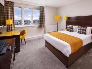 a hotel room with a bed and a desk and windows at Mercure Ayr Hotel in Ayr