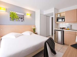 a bedroom with a large white bed and a kitchen at Aparthotel Adagio Access Nice Magnan in Nice