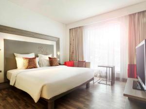 a hotel room with a large bed and a television at Novotel Banjarmasin Airport in Banjarbaru