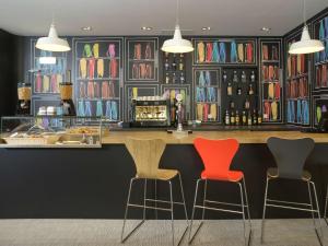a bar with three chairs in front of a counter at Hotel Ibis Lisboa Parque das Nações in Lisbon