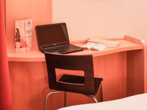 a laptop computer sitting on a desk with a chair at ibis Bordeaux Saint Emilion in Saint-Émilion