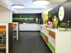 a kitchen with white cabinets and orange and green at ibis Styles Luzern in Lucerne