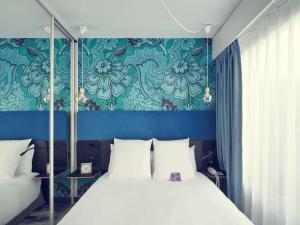 um quarto com uma cama com uma parede azul em Mercure Paris Bastille Saint Antoine em Paris