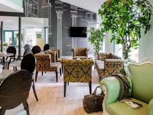 un groupe de chaises et de tables dans une pièce dans l'établissement ibis Styles Speyer, à Speyer