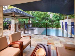 a patio with chairs and a fence and a pool at Pullman Port Douglas Sea Temple Resort and Spa in Port Douglas