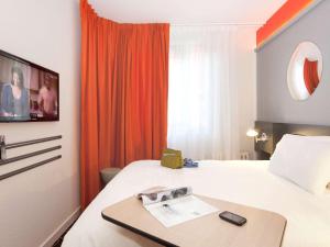 una camera d'albergo con letto e TV a parete di ibis Styles Roanne Centre Gare a Roanne