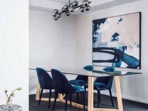 a dining room with a glass table and blue chairs at Quay West Suites Melbourne in Melbourne